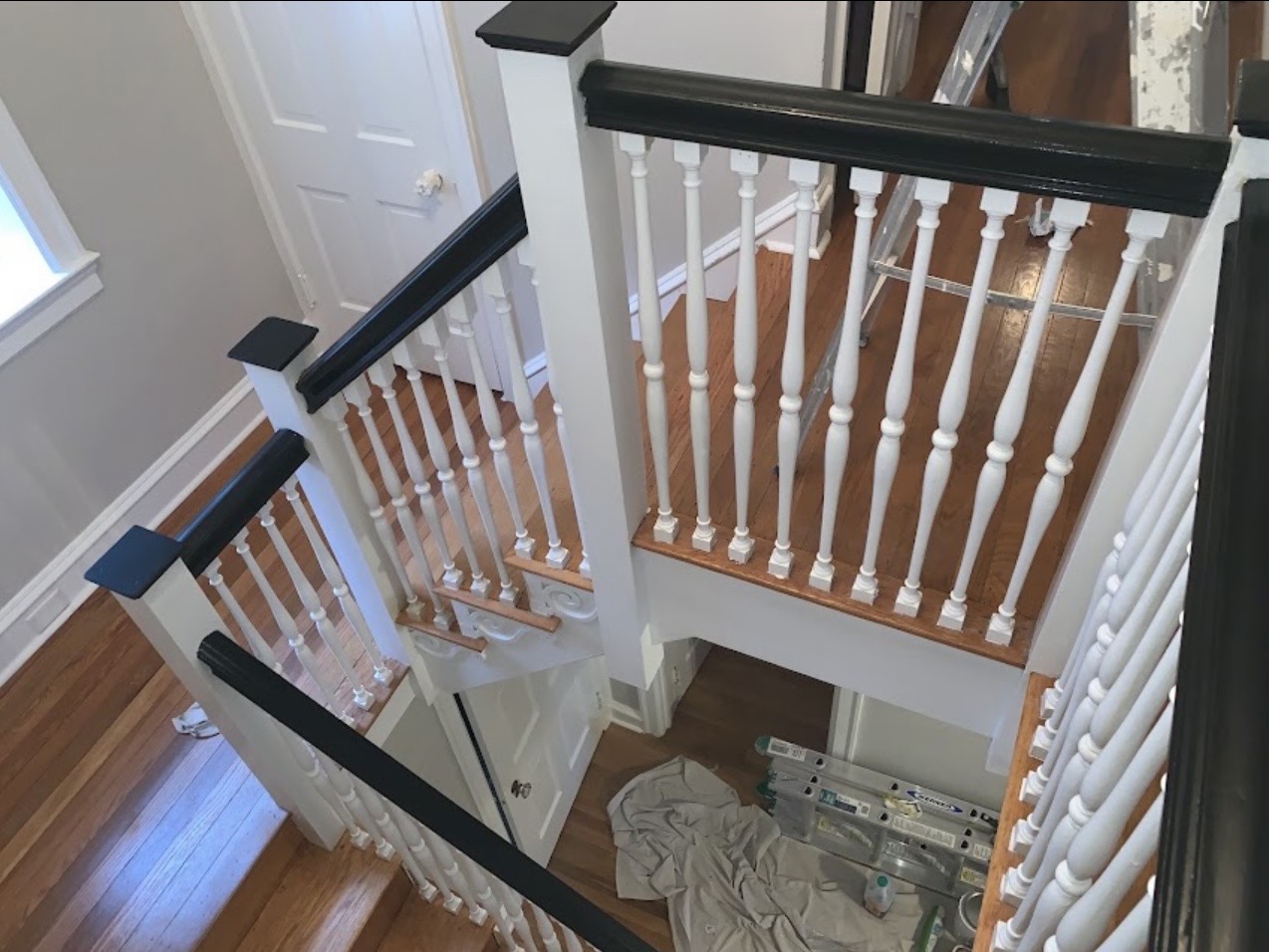 Painted staircase with black handrail and white spindles